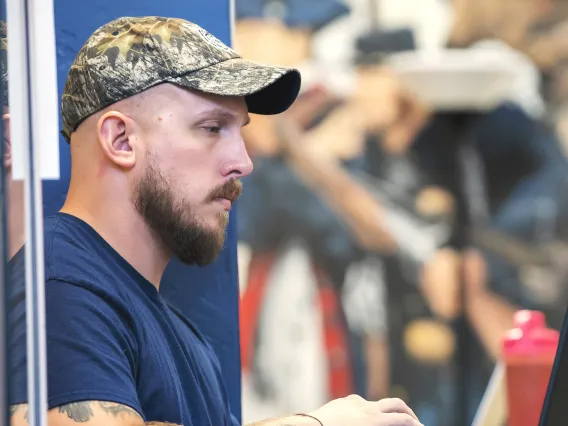 Veteran working on laptop in VET Center with mural in background