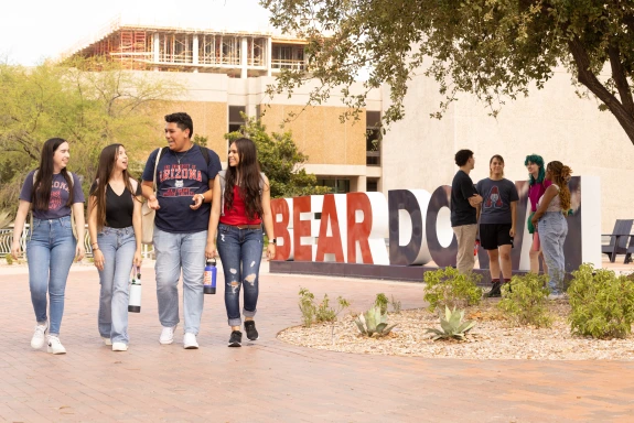 Happy students walking in front of Bear Down sign